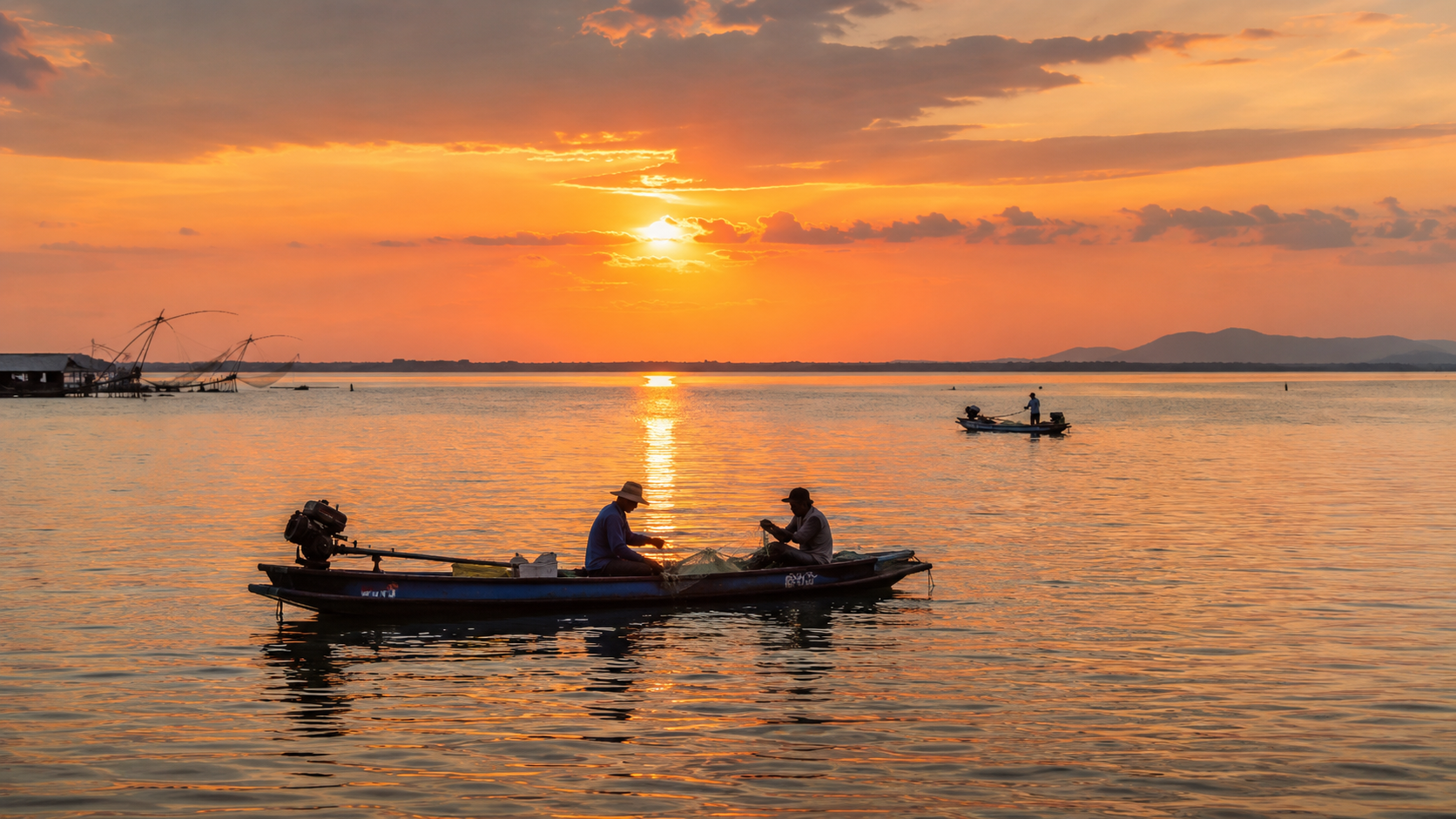 Fishing boats crossing Nong Han Lake during a warm sunrise.